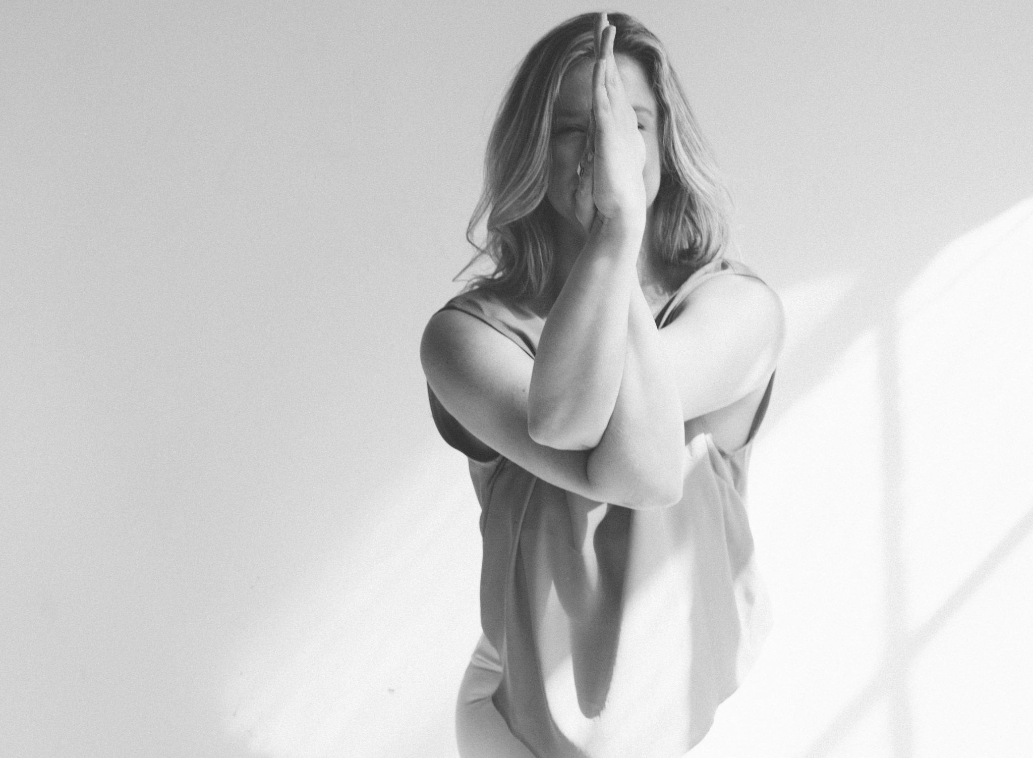 b+w photo of woman doing yoga with arms crossed which cover her face