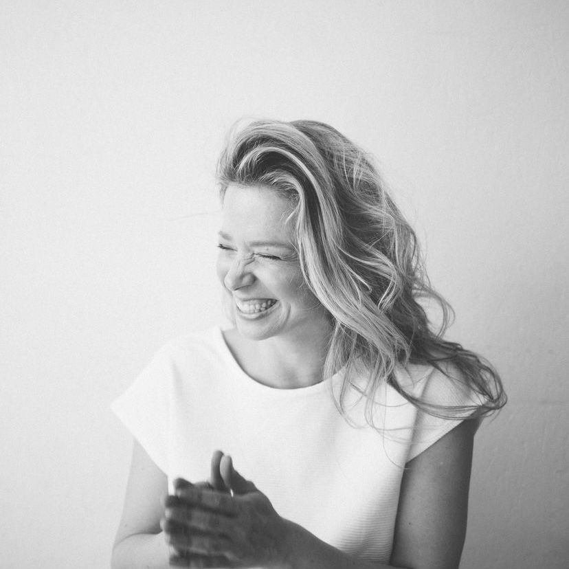 black and white photo of woman laughing hands in prayer in a white short sleeve top