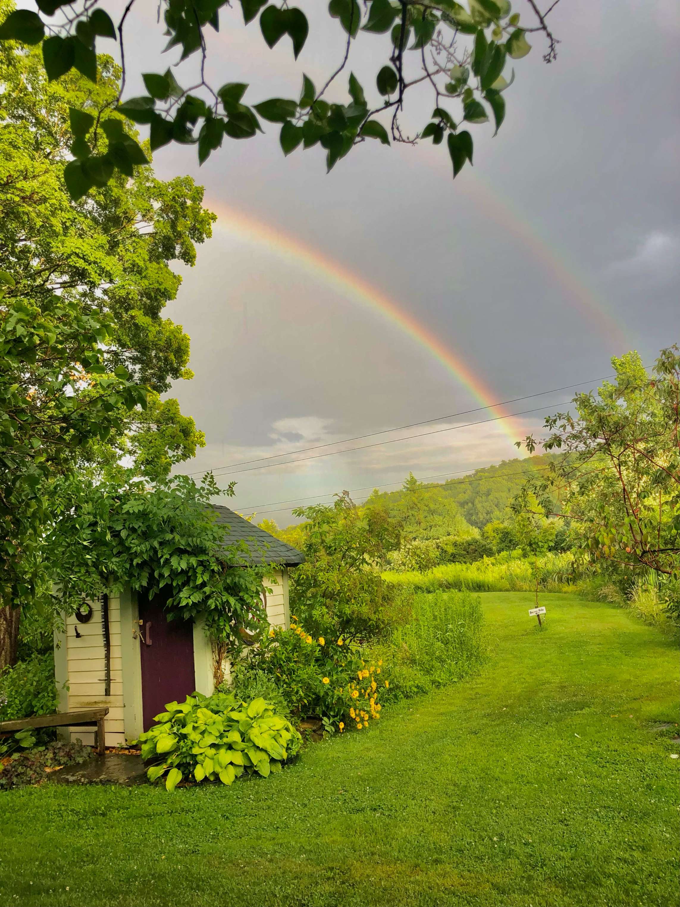 double rainbow behind a small shed
