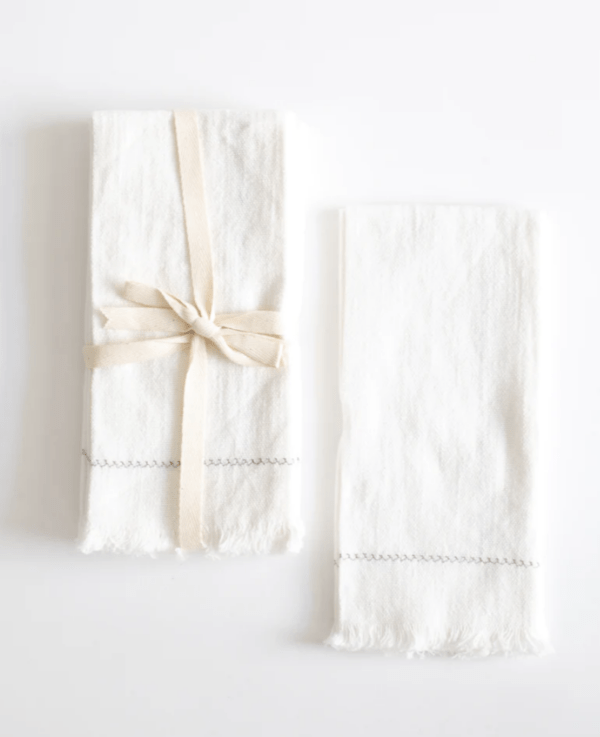 two sets of white napkins, the left is tied with ribbon