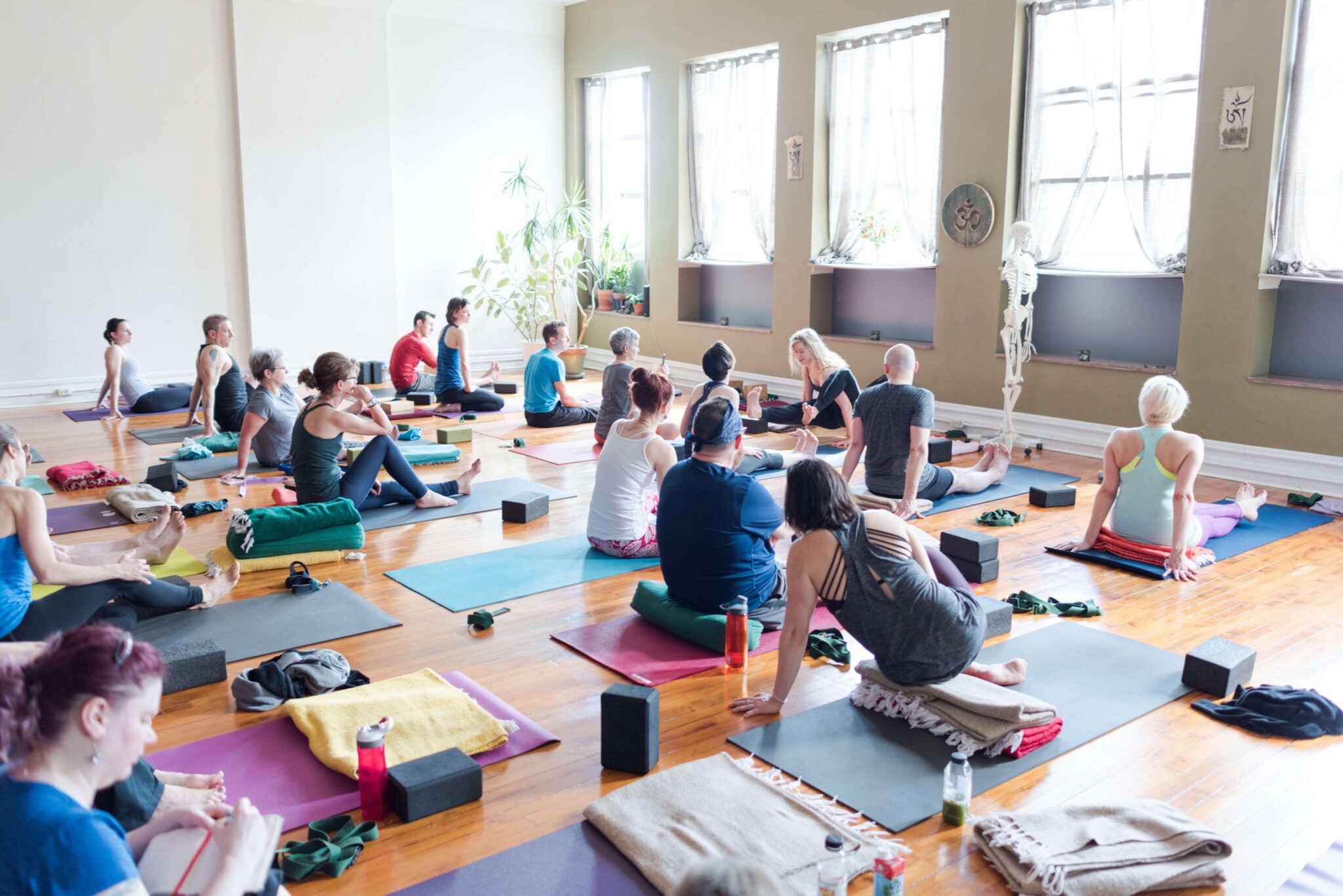 yoga class in room with big windows with teacher demonstrating arm balance