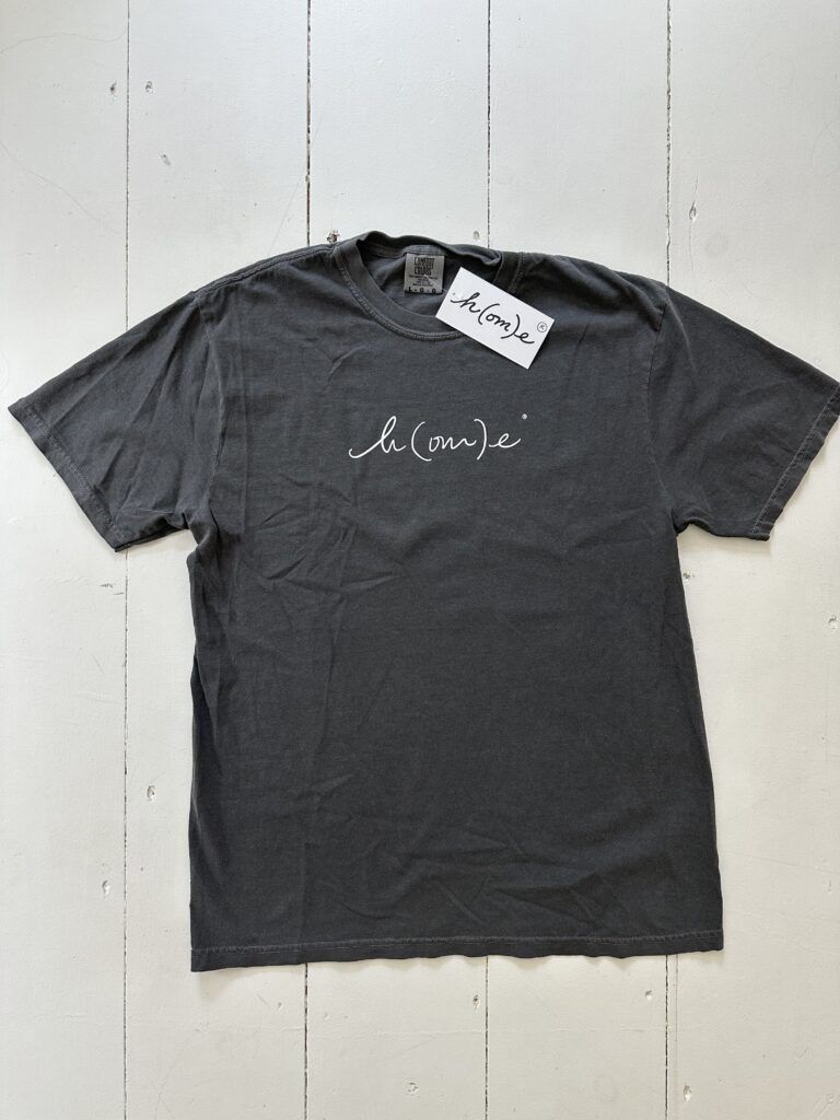 gray t-shirt with logo h(om)e on front on white wood floor