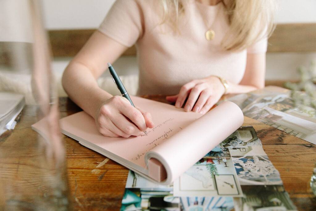 woman writing on pink pad wearing matching color shirt